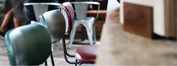Tabourets de bar en cuir et métal en premier plan devant des chaises industielles