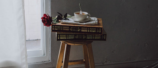 Tabouret en bois massif sur lequel reposes des livre anciens et une tasse 