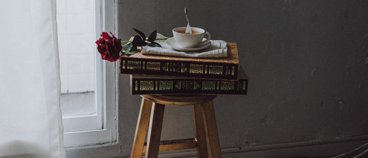 Tabouret en bois massif sur lequel reposes des livre anciens et une tasse 